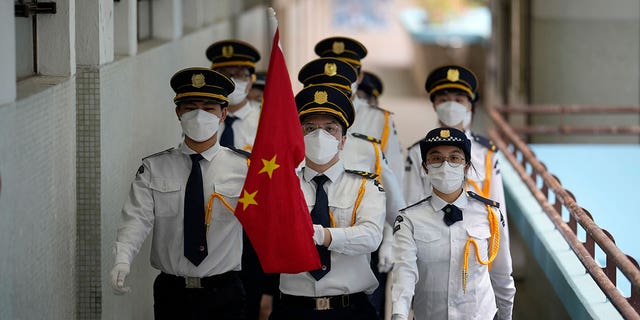 Students wearing face masks attend a Chinese national flag raising ceremony during at a secondary school to mark the 25th anniversary of Hong Kong handover to China, in Hong Kong, Thursday, June 30, 2022. 