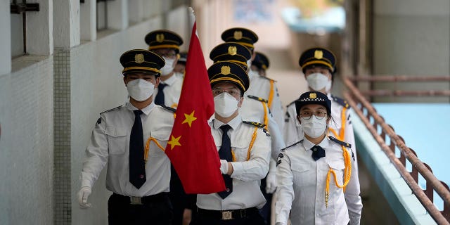 Students wearing face masks attend a Chinese national flag raising ceremony during at a secondary school to mark the 25th anniversary of Hong Kong handover to China, in Hong Kong, Thursday, June 30, 2022. 