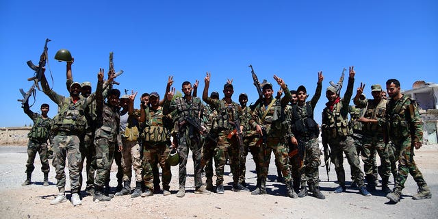 Members of the Syrian army gesture while they are deployed in Deraa al Balaad, Syria, in this handout released by SANA Sept. 8, 2021. 