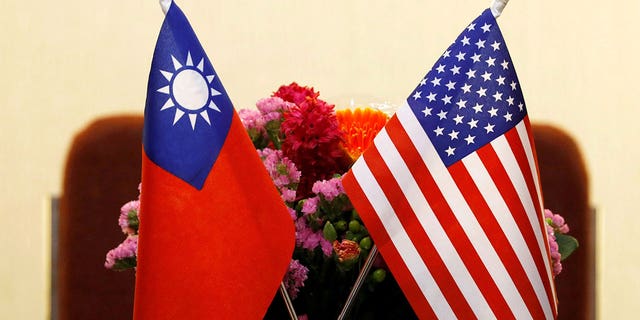 Taiwanese and American flags with flowers behind them