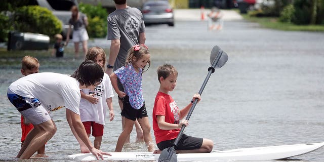 Kyle Hilderbrandt, right, paddles on NE 2nd Ave., in Oakland Park, Fla., Saturday, June 4, 2022. Tropical weather brought heavy rain and flooding to South Florida.