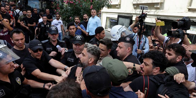 Politieagenten voorkomen dat journalisten filmen en foto's maken van activisten die worden vastgehouden terwijl ze probeerden te marcheren in een pride-parade, die werd verboden door de lokale autoriteiten, in het centrum van Istanbul, Turkije 26 juni 2022. (REUTERS/Umit Bektas)