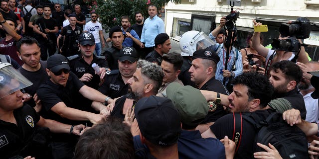 Police officers prevent journalists from taking photographs of detained activists while trying to film and march in a Pride Parade that was banned by local authorities on June 26, 2022, in central Istanbul, Turkey.  (Reuters/Umit Bektas)