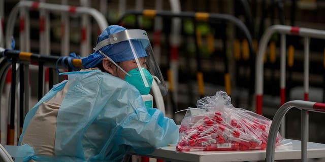 A volunteer in protective gear waits for residents at a coronavirus testing facility in Beijing, Thursday, June 9, 2022.