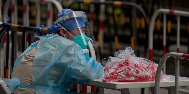 A volunteer in protective gear waits for residents at a coronavirus testing facility in Beijing, Thursday, June 9, 2022.