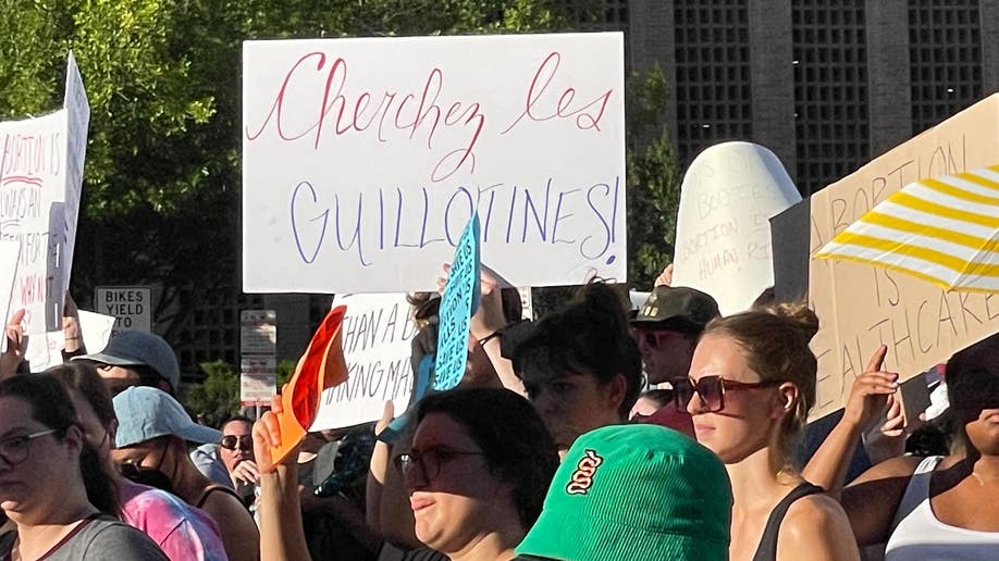 A sign reads, 'Cherez les Guillotines!'