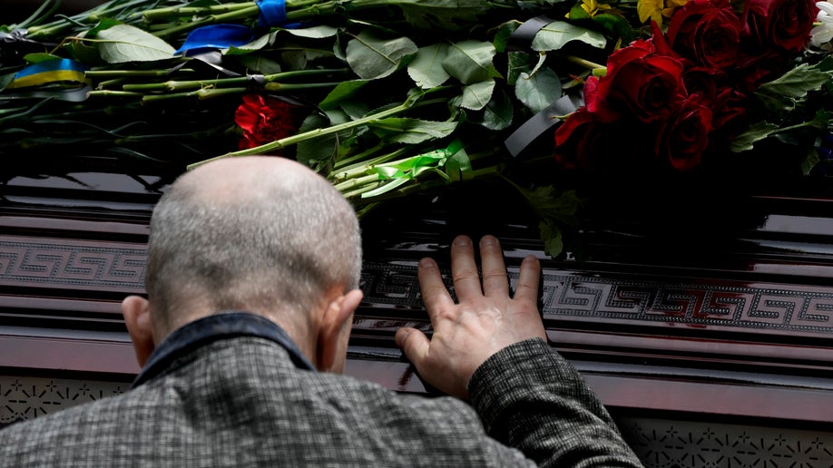 Ukraine man touching coffin 
