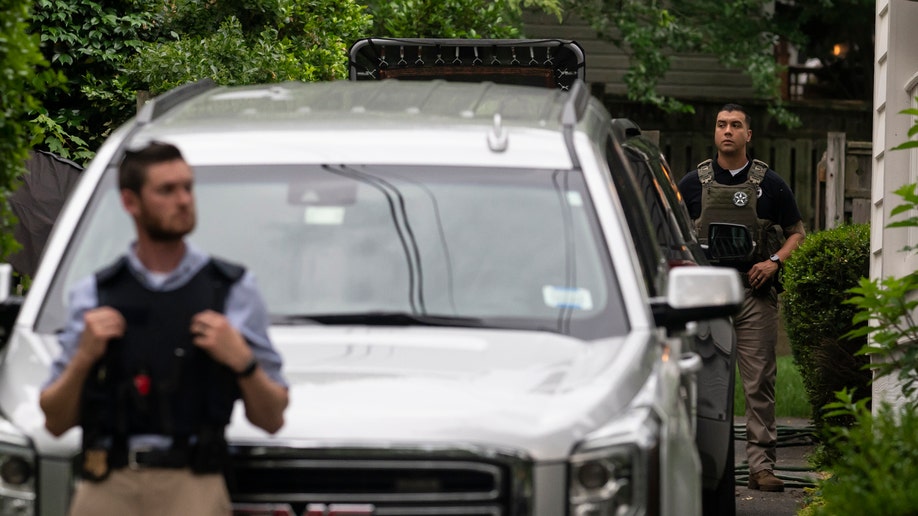 Law enforcement officers stand guard as protesters march past Supreme Court Justice Brett Kavanaugh's home