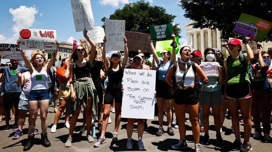 Protesters hold signs in front of the Supreme Court building