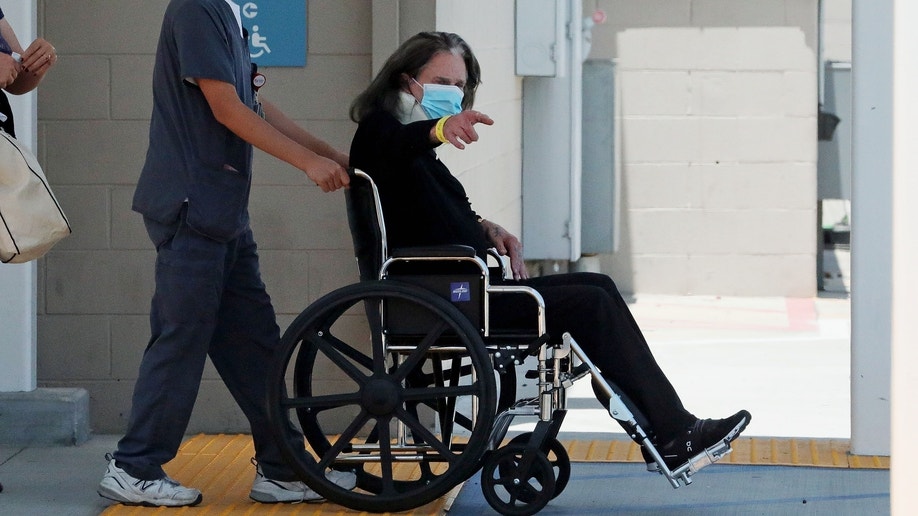 Ozzy Osbourne signaled to a waiting vehicle post surgery