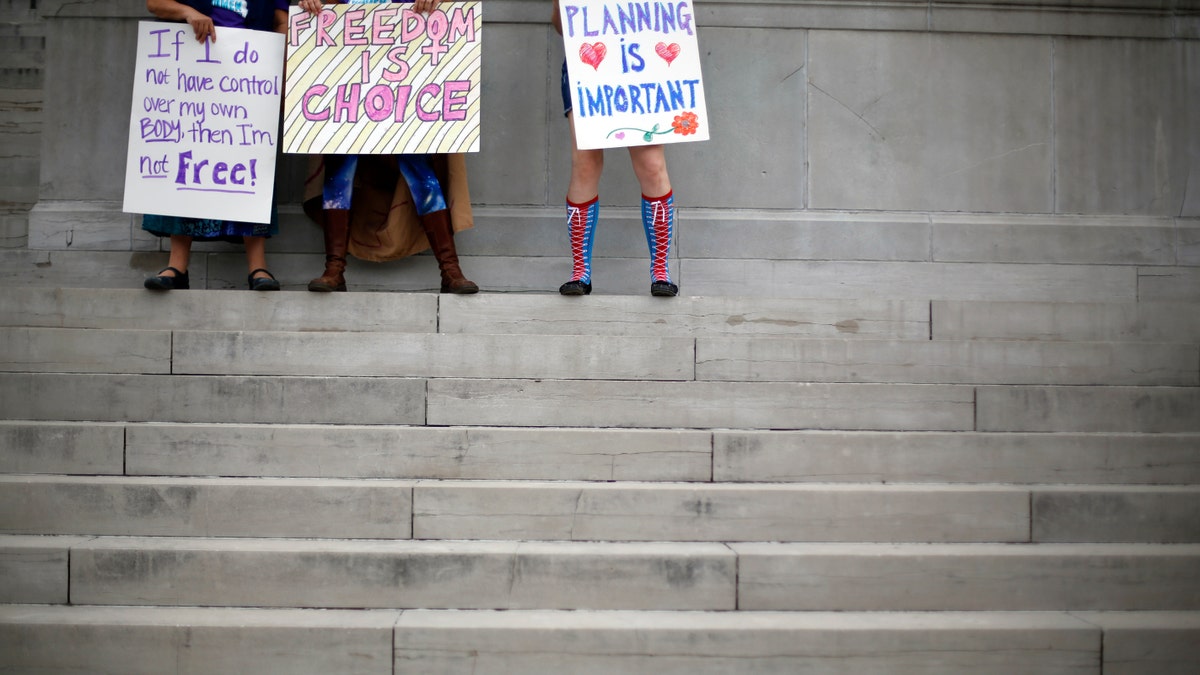 Abortion rights activists hold signs as they stand on the steps of the Missouri Capitol, Sept. 10, 2014, in Jefferson City, Mo.