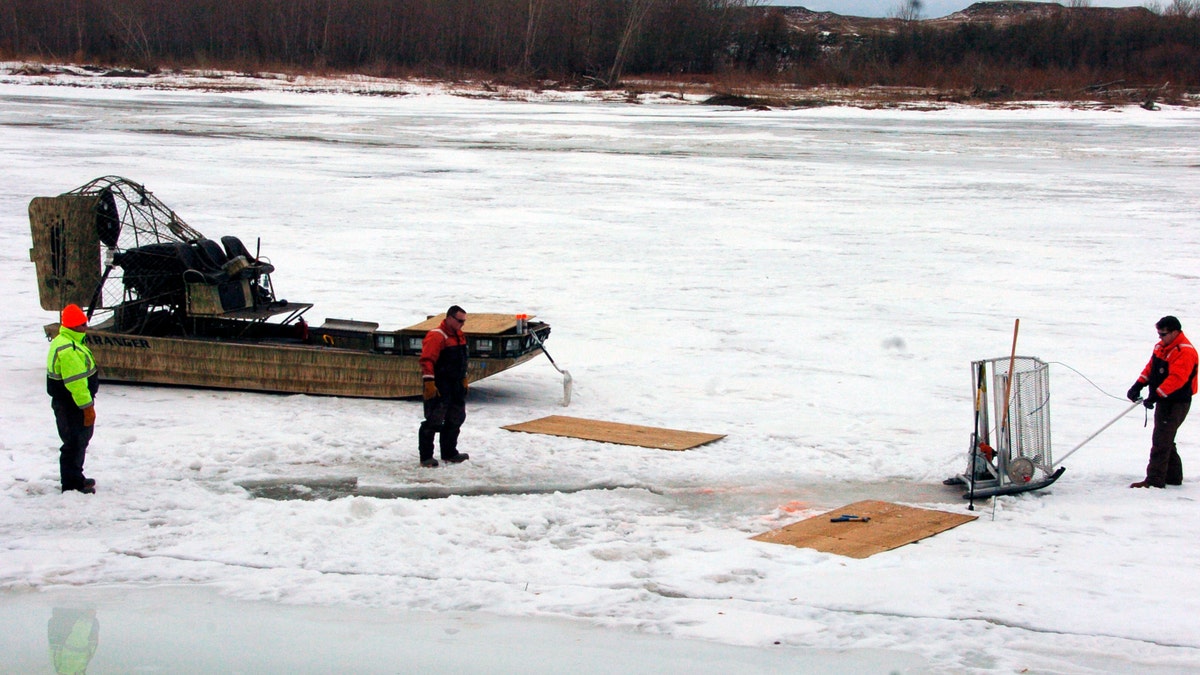 cleanup workers cut holes into the ice