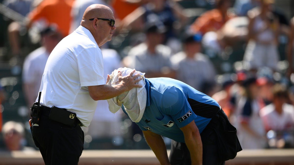 Baltimore Orioles head trainer Brian Ebel, left, helps home plate 
