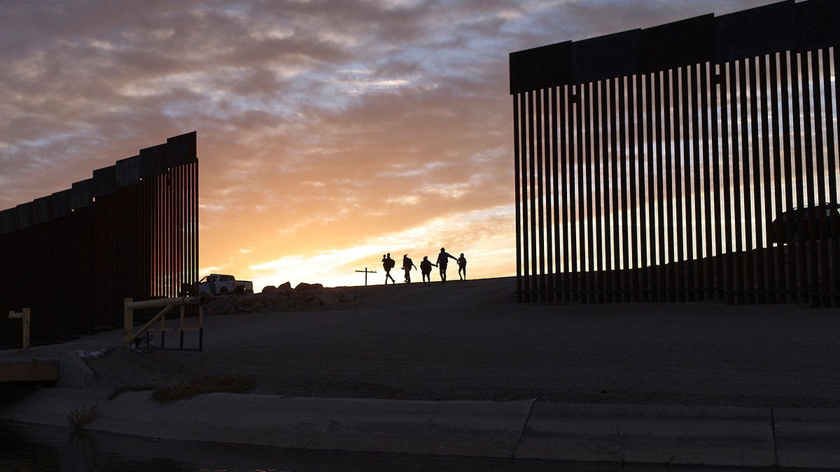 Una foto de una puesta de sol detrás de una parte del muro fronterizo de Yuma