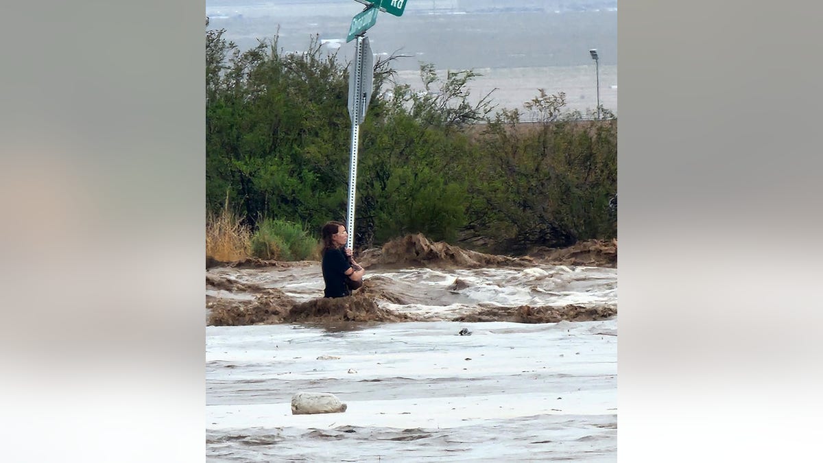 Woman clinging to signpost in flood