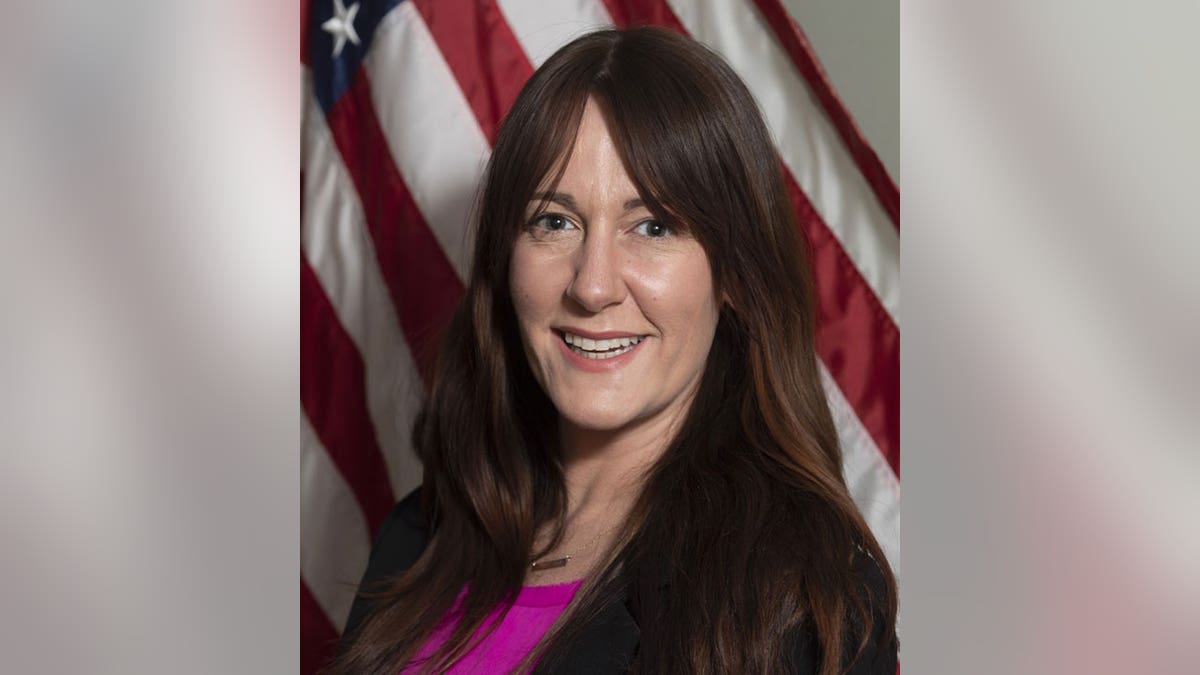 Amy DeGise smiles in front of American flag