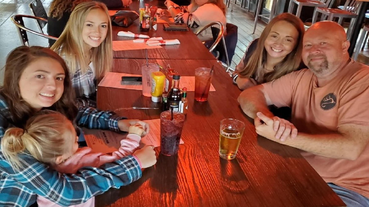 Breanna Chadwick, Heath Chadwick, and their family sitting around a table at a restaurant