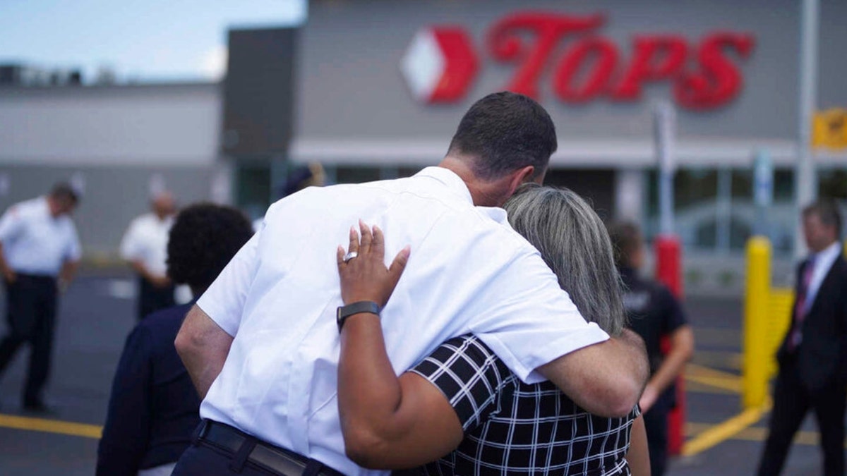 People hug at a ceremony outside the Tops Market attacked in May