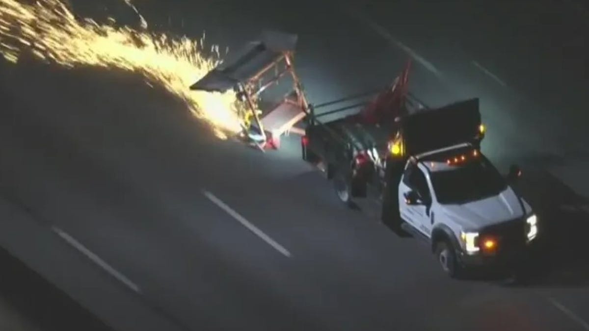 A work truck with sparks flying is seen driving down a California freeway