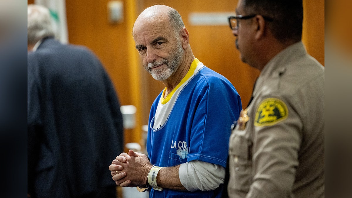 Jeffrey Cooper arrives in court in handcuffs in prisoner garb