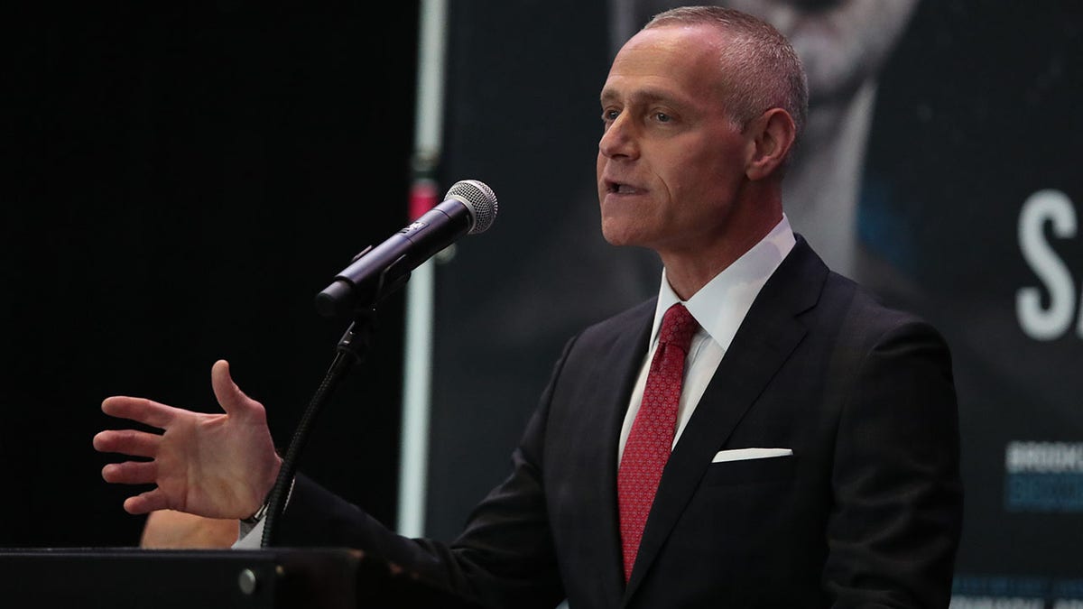 Brett Yormark gestures in a black suit with a red tie as he talks to the media in 2019