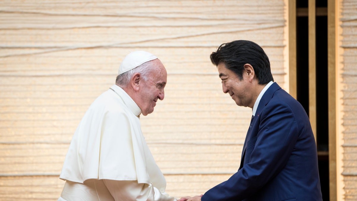 Former Japanese Prime Minister Shinzo Abe shakes hands with Pope Francis in 2019