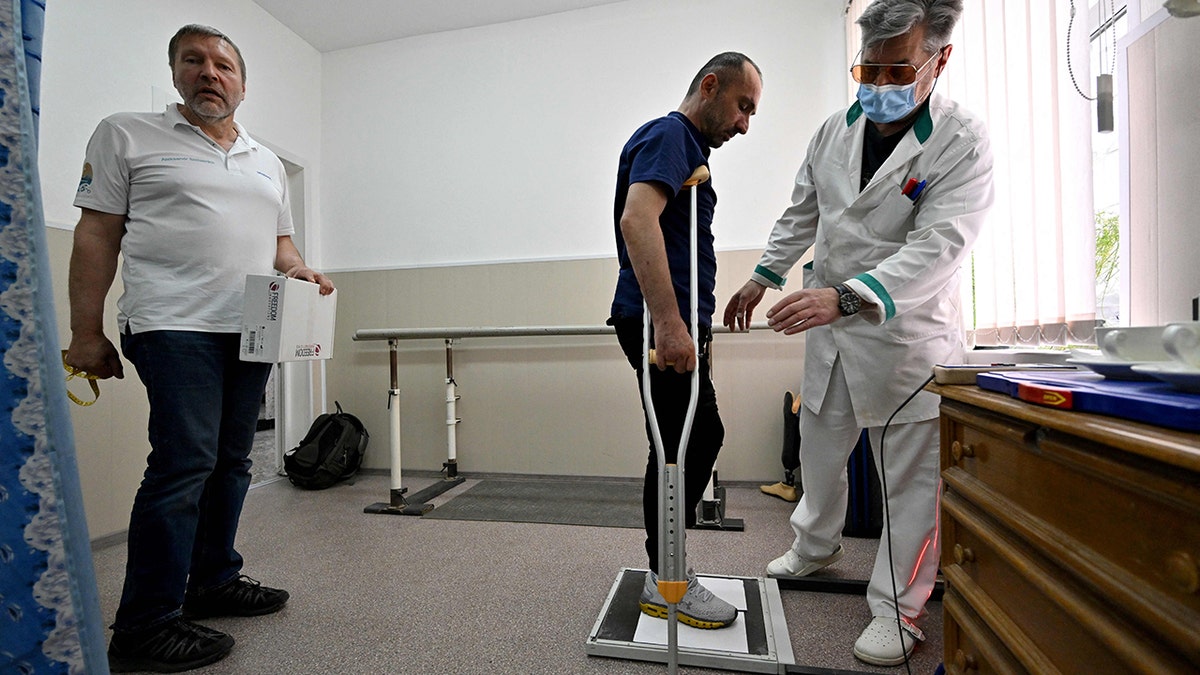 A Ukrainian amputee standing with the use of crutches and a prosthetic