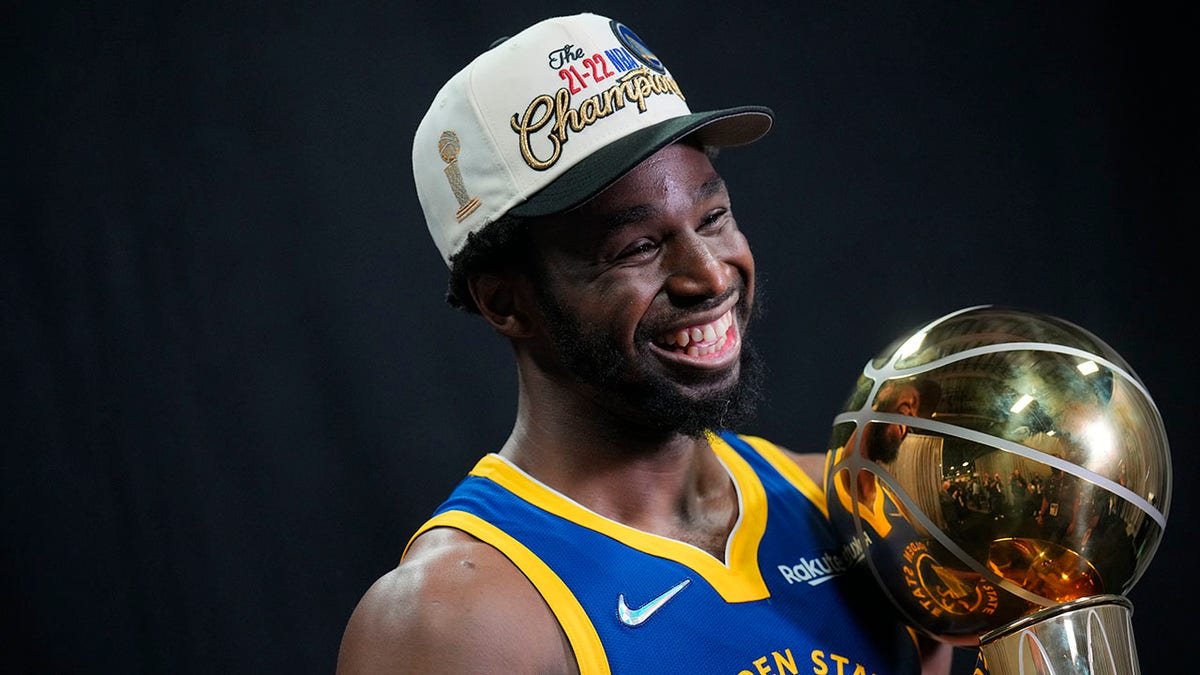 Andrew Wiggins smiles while holding the Larry O'Brien Championship Trophy