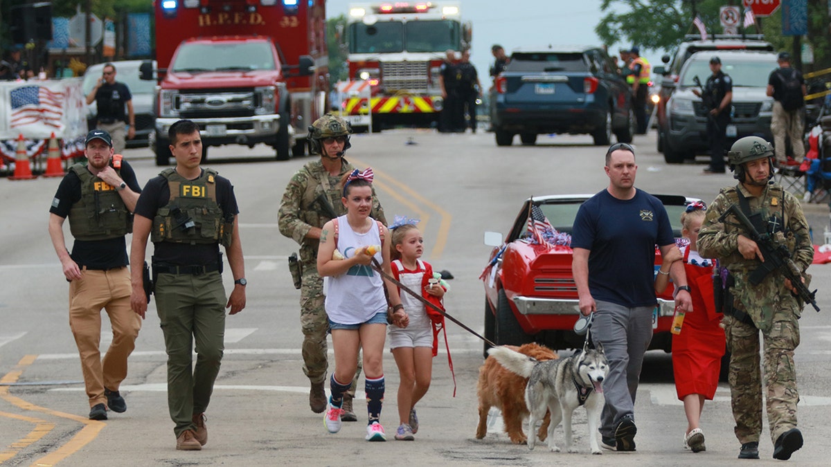 Law enforcement walks with family away from Highland Park shooting scene