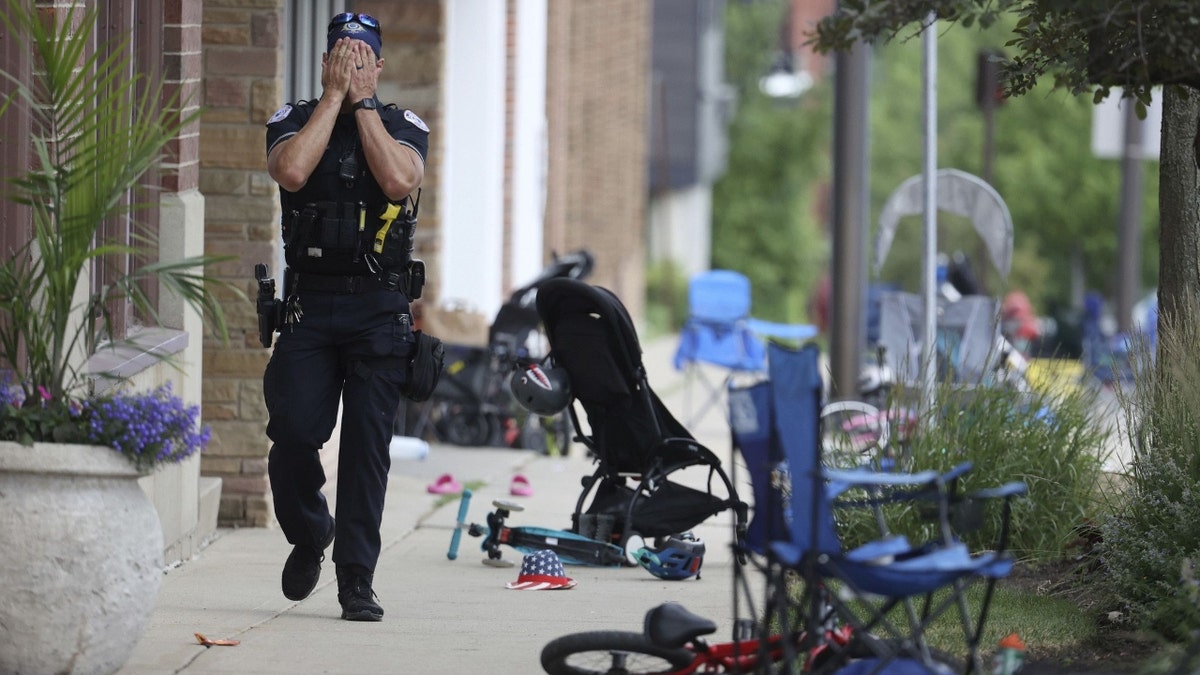 A Lake County, Illinois, police officer walks down Central Avenue in Highland Park on July 4, 2022, after a shooter fired on the northern Chicago suburb's Fourth of July parade. 