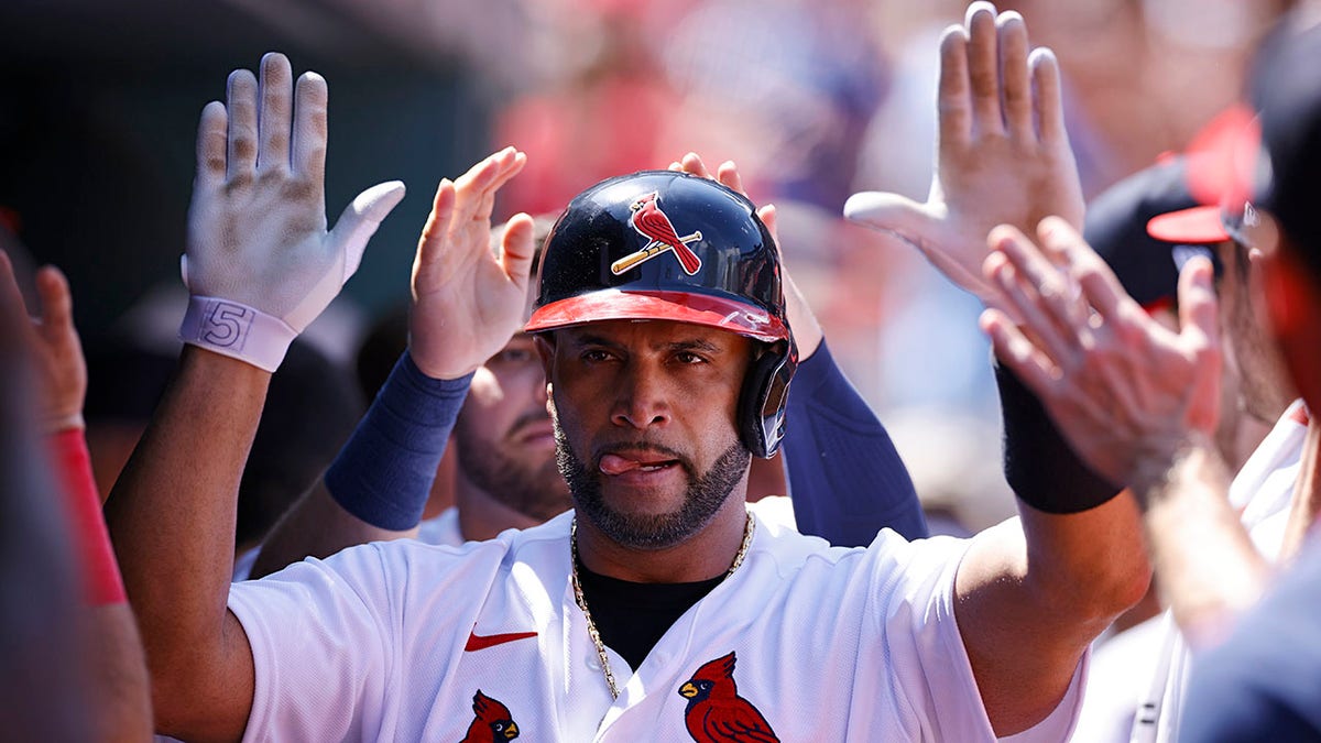 Albert Pujols gives high fives after hitting a solo home run against the Phillies