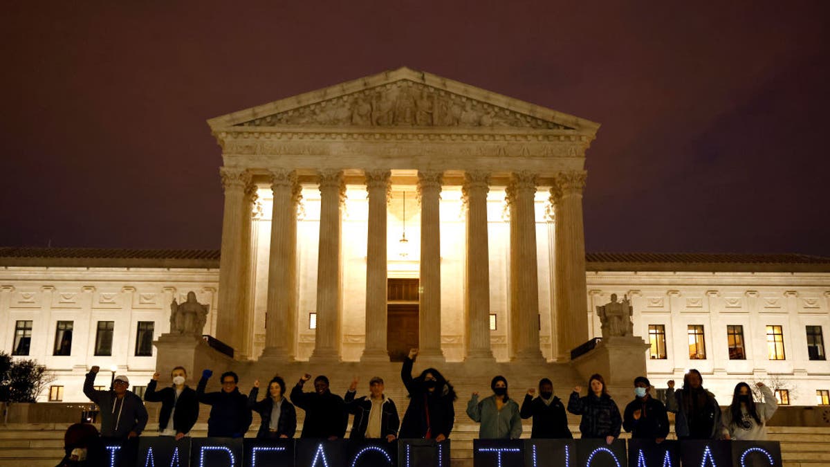 Activists hold a sign reading, 'Impeach Thomas' in front of the Supreme Court building