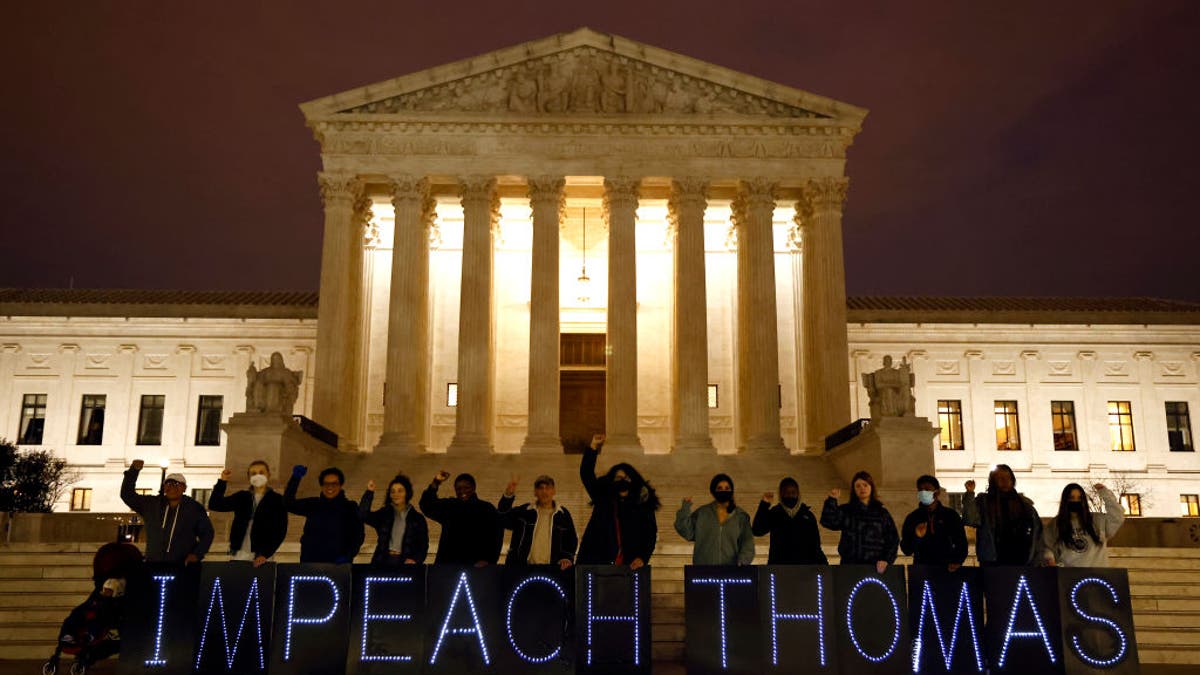 Activists hold a sign reading, 'Impeach Thomas' in front of the Supreme Court building