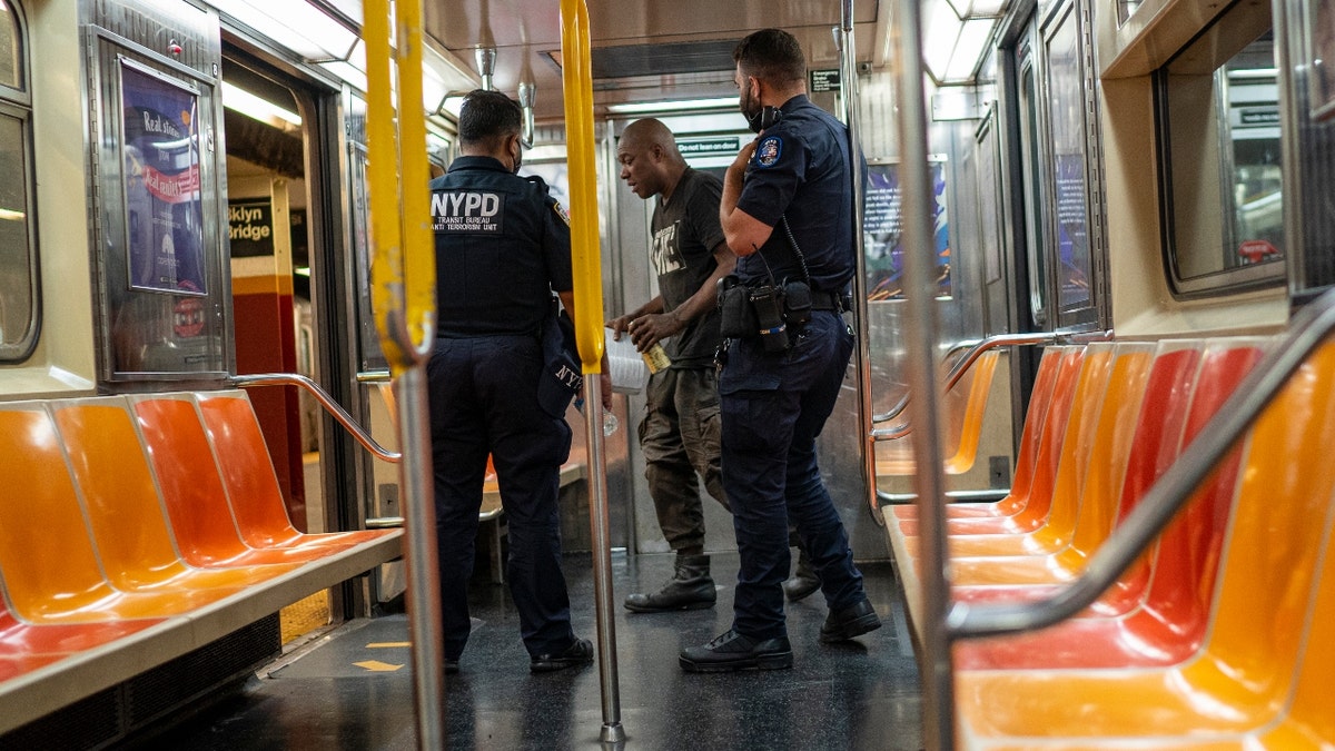 New York Police Department officers order a subway traveler to leave the car