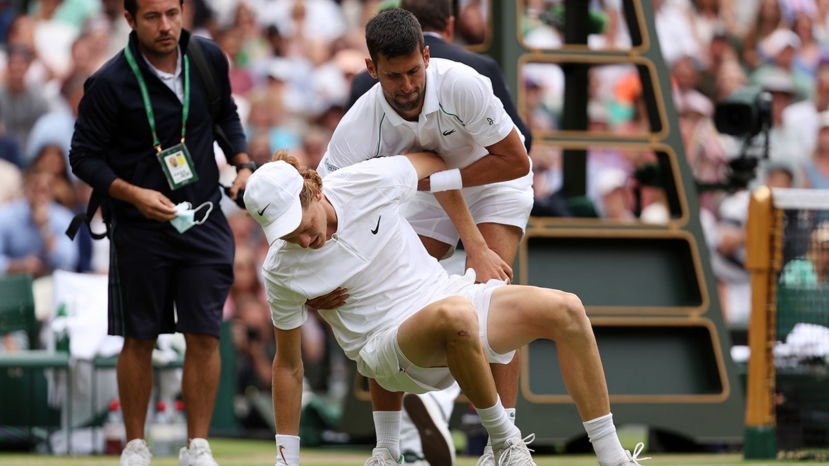 Novak Djokovic helps Jannik Sinner up