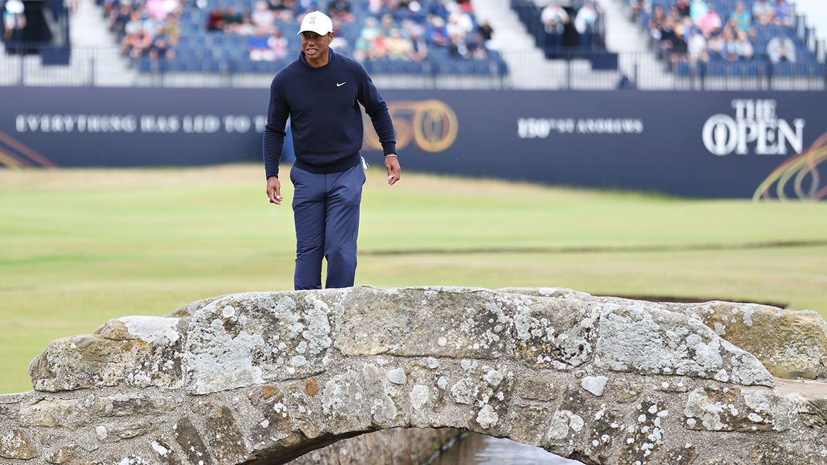 Tiger Woods, in a white hat, looks out over St Andrews Old Course