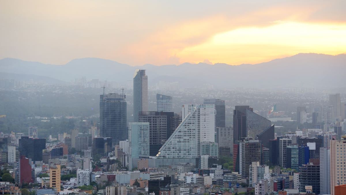 Aerial view of Mexico City with the sun behind mountains in the background