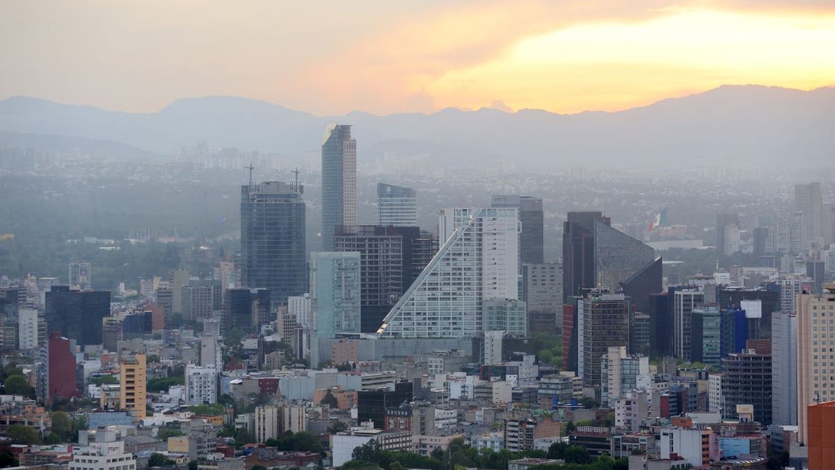 Aerial view of Mexico City with the sun behind mountains in the background