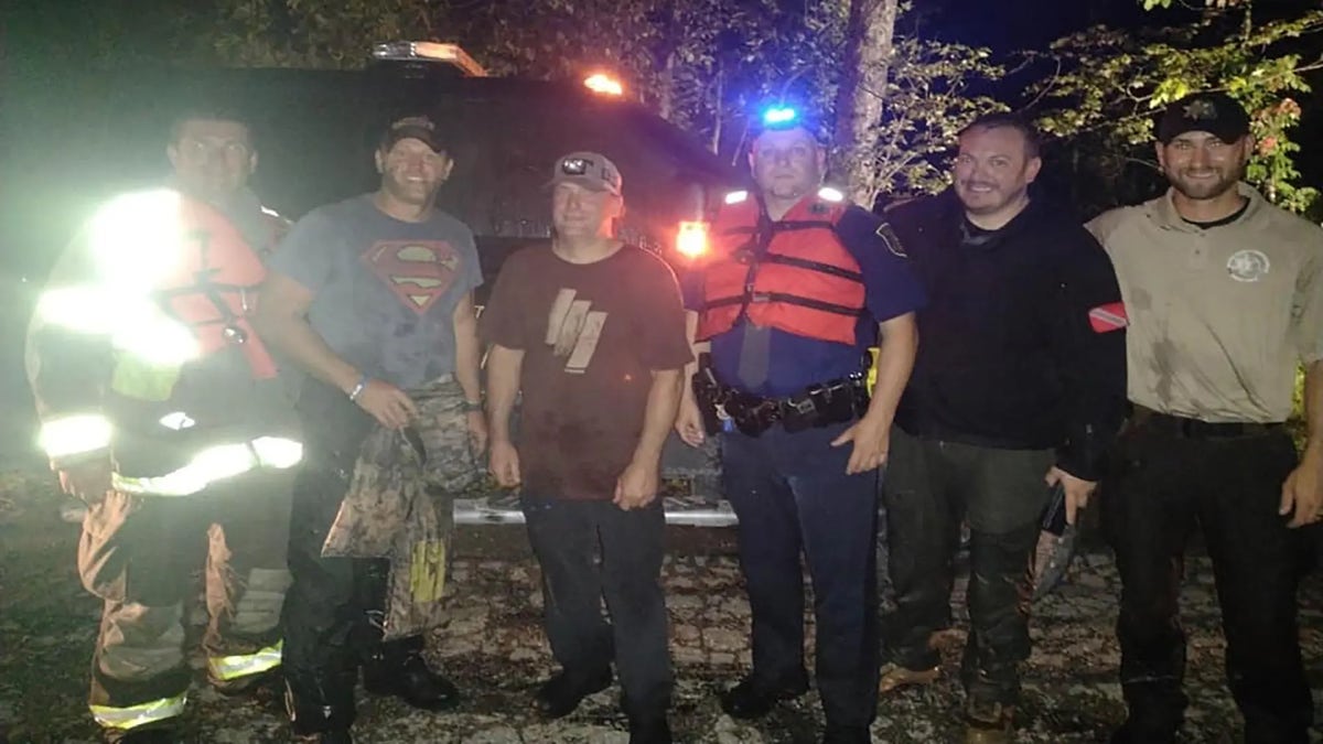 People rescued from a muddy Michigan river pose with first responders