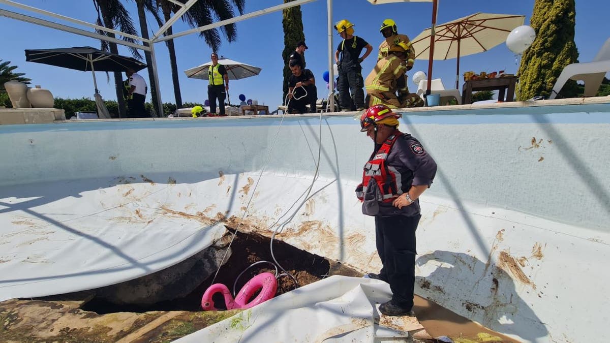 A rescuer views pool sinkhole damage