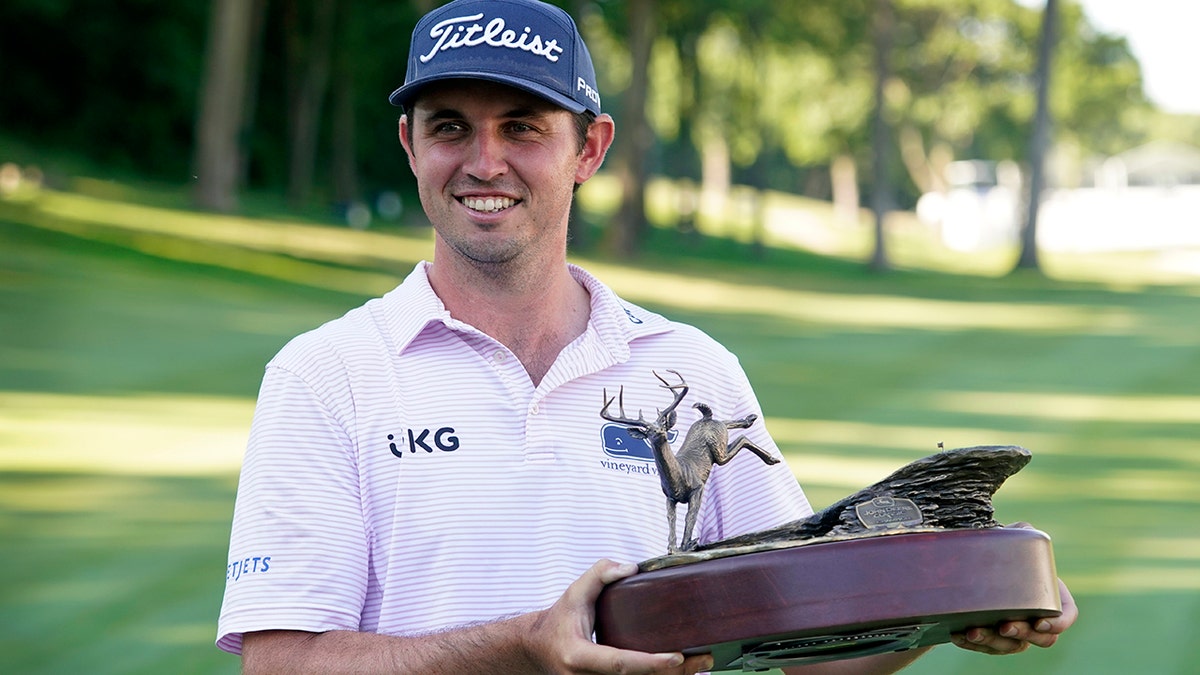 JT Poston holds the John Deere Classic trophy