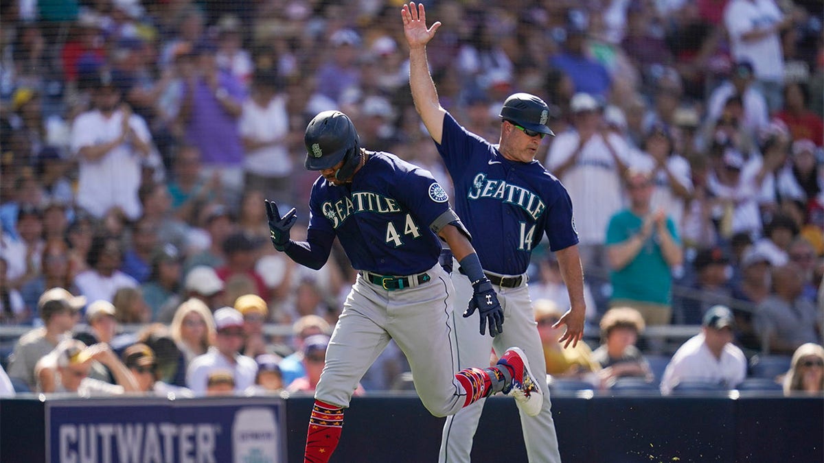 Julio Rodriguez celebrates with third base coach