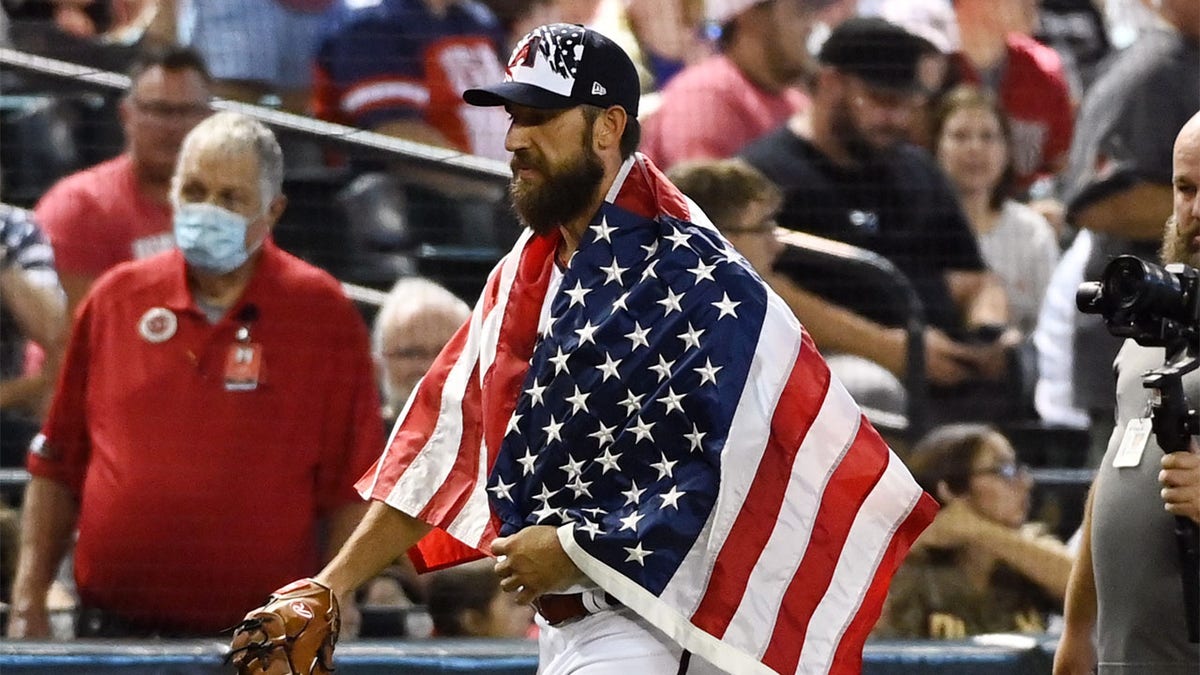 Madison Bumgarner walks with the American flag draped on his shoulders