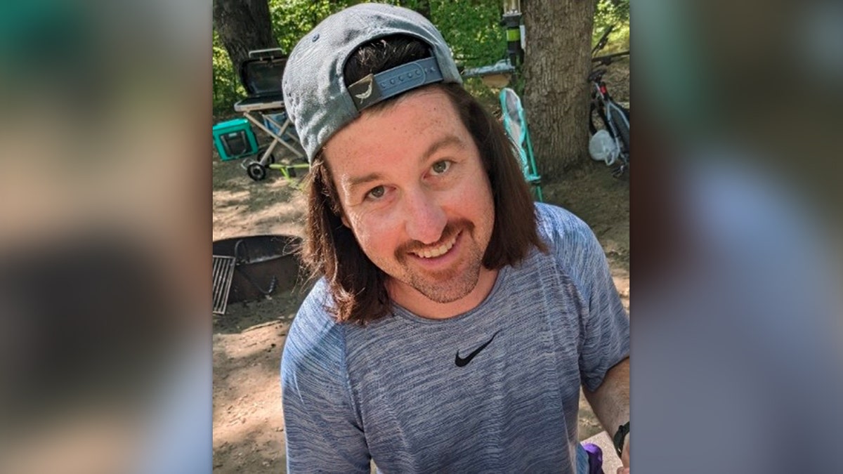 Logan Sweet smiles wearing a backwards hat and a gray t-shirt