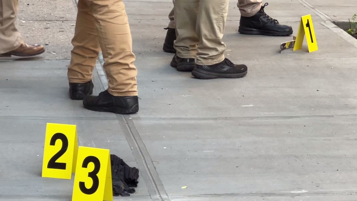 Police examine evidence on the ground at the scene of Nathaniel Rivers' murder