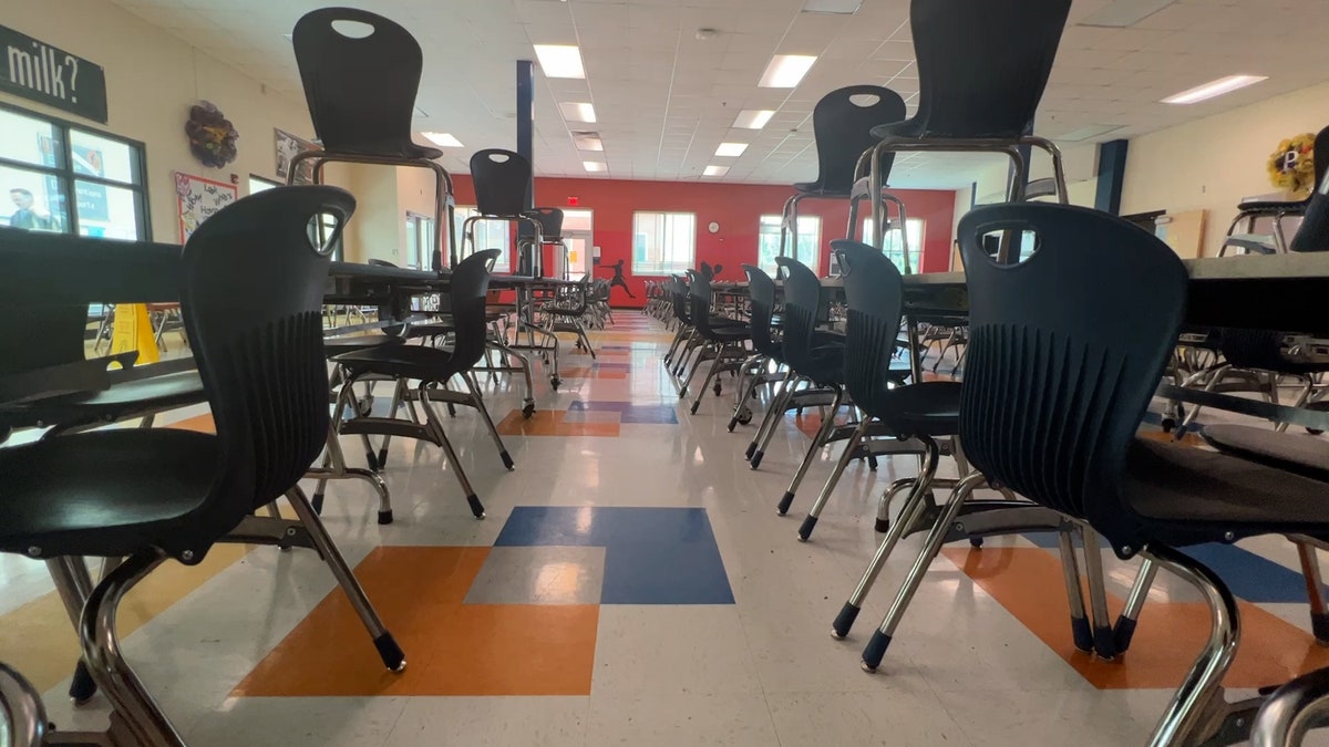 Tables and chairs sit in an empty classroom