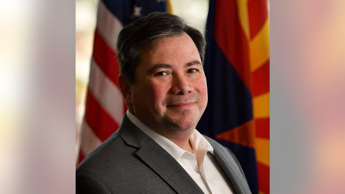 Rene Lopez in a suit in front of an American and Arizona flag