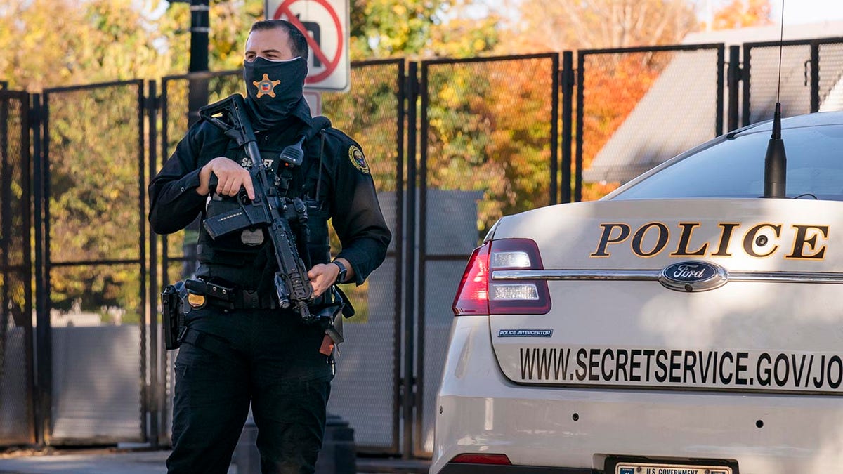 Uniformed Secret Service agent with rifle standing near a cruiser