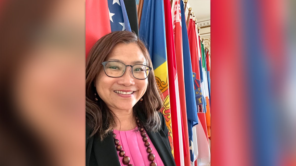 Shandra Woworuntu smiles in front of a row of international flags