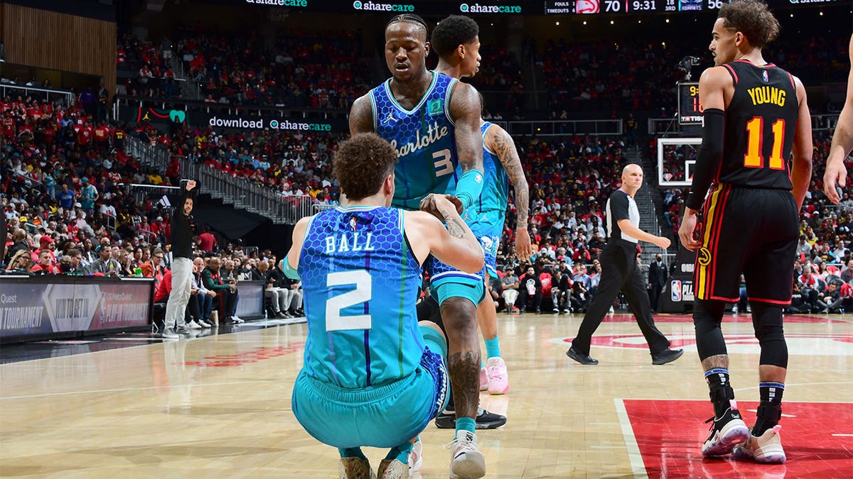 Terry Rozier helps LaMelo Ball up to his feet